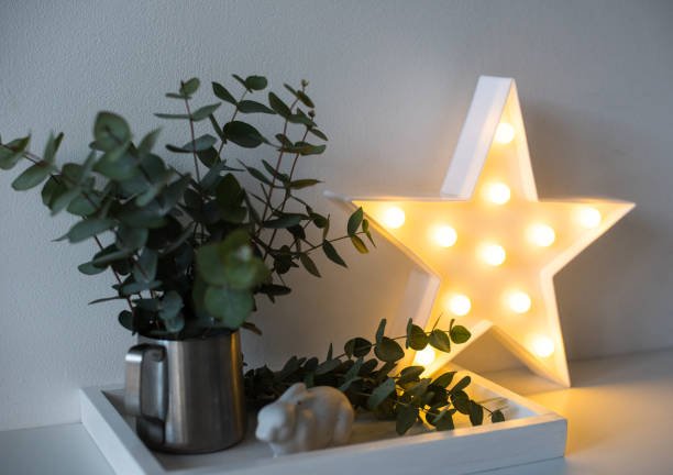 Warm glowing star-shaped light on a shelf with a small green plant.